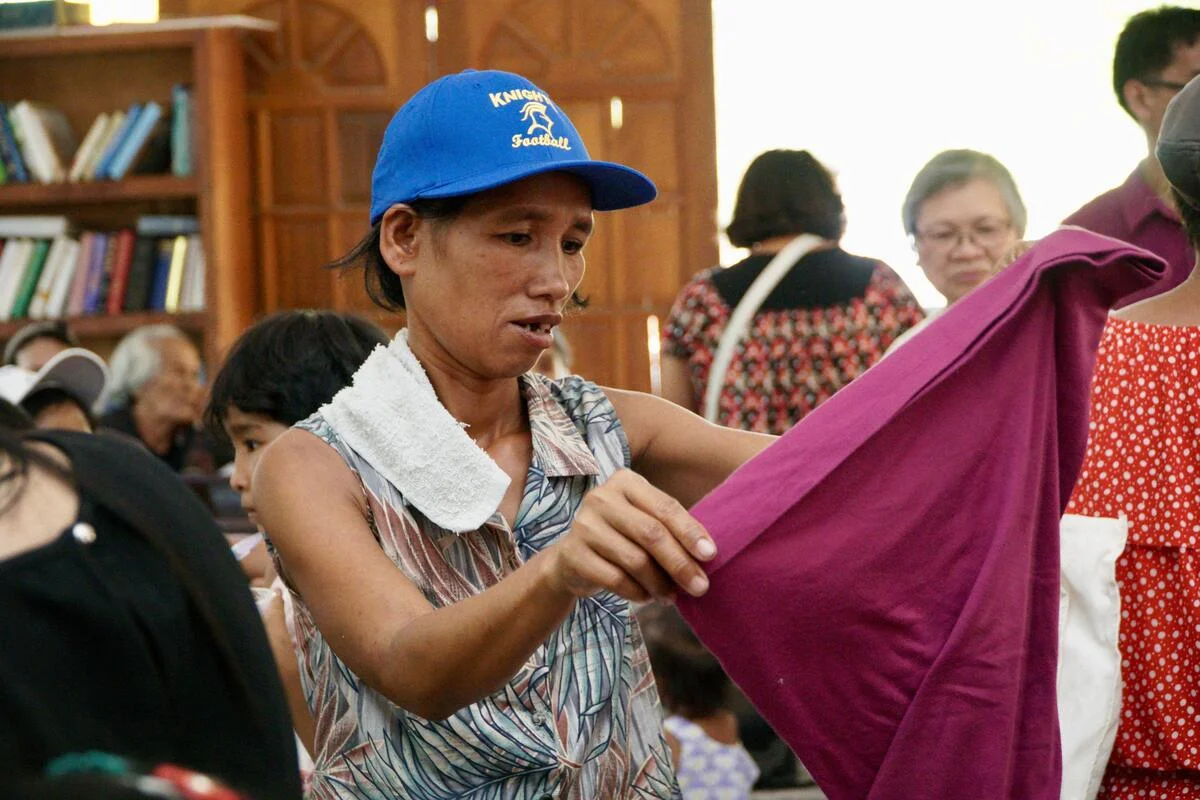 An adult holding up a garment during a community clothing gathering
